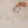 Wasser wird in Glasvase mit Herzprint gegossen, minimalistisches Setting