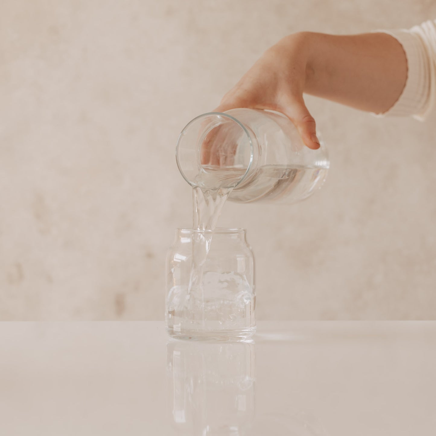 Wasser wird in Glasvase mit Herzprint gegossen, minimalistisches Setting