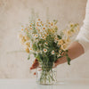 Gefüllte Glasvase mit buntem Blumenstrauß und Herzmuster