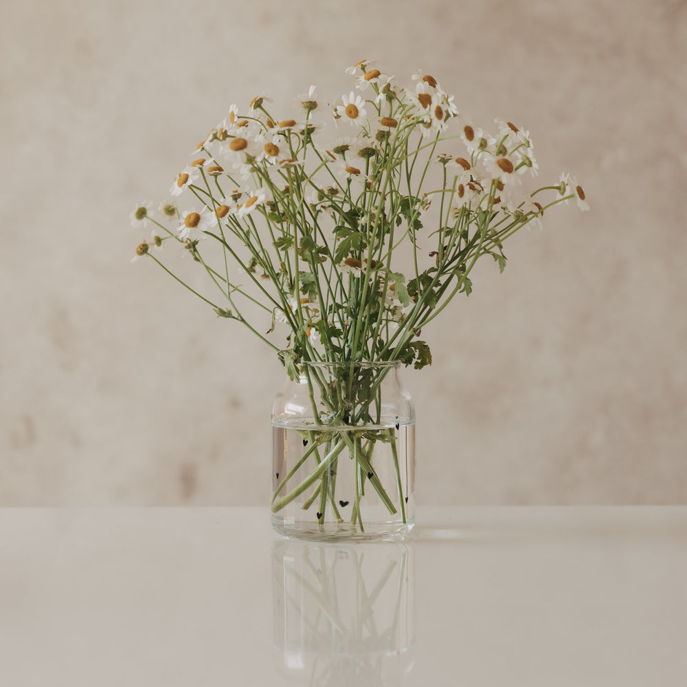 Glasvase mit Herzmotiv, gefüllt mit Blumenstrauß aus Kamille