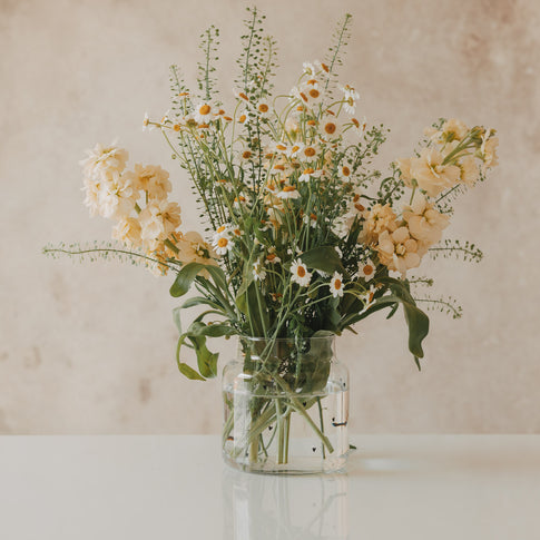 Glasvase mit schwarzen Herzen und vollem Blumenarrangement