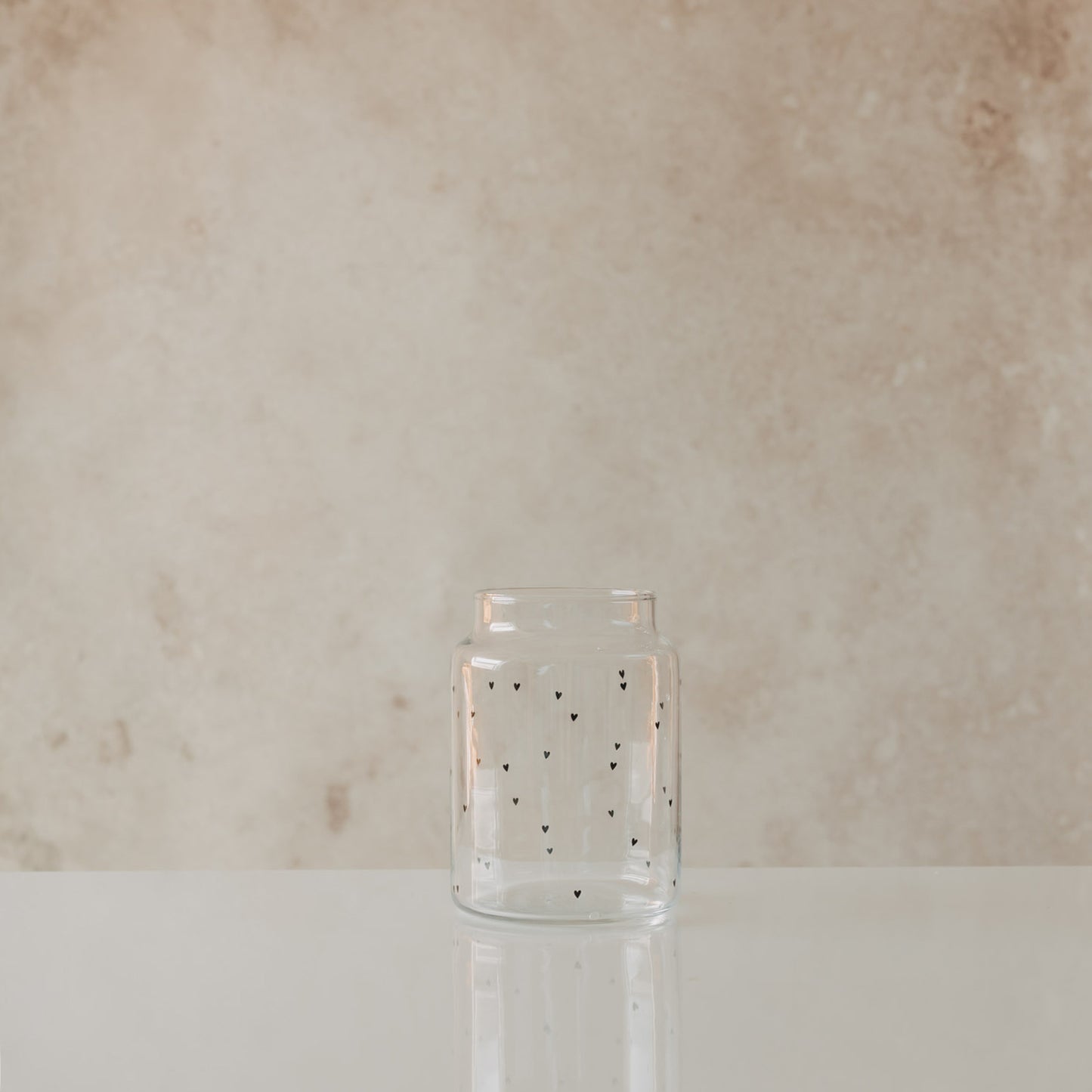 Glasvase mit schwarzem Herzmuster minimalistisch auf hellem Hintergrund