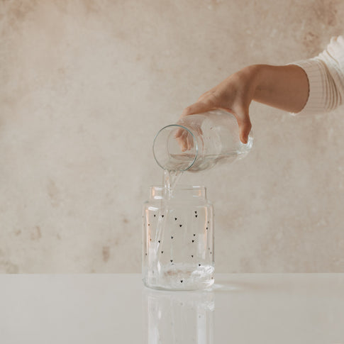 Glasvase mit Herzprint wird mit Wasser befüllt
