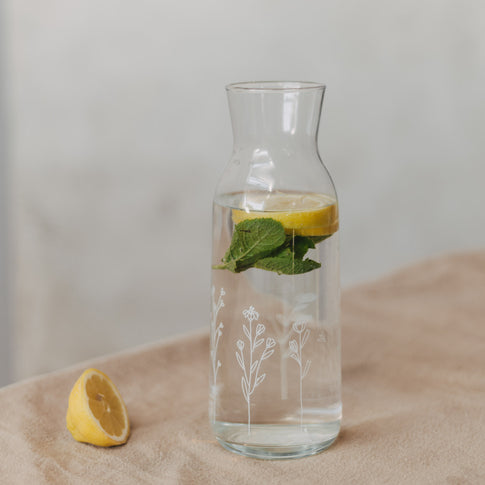 Karaffe mit Wasser, Zitrone und Minze auf hellem Untergrund