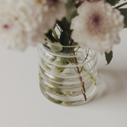 Nahaufnahme der geriffelten Bubble Vase aus Glas mit Blumenstrauß und sichtbaren Blumenstielen im Wasser.