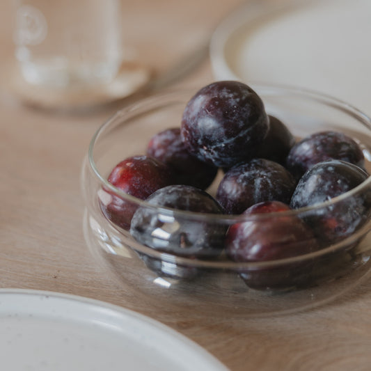 Glas-Schale Bubbles mittel mit frischen Pflaumen auf einem Holztisch – stilvoll serviert