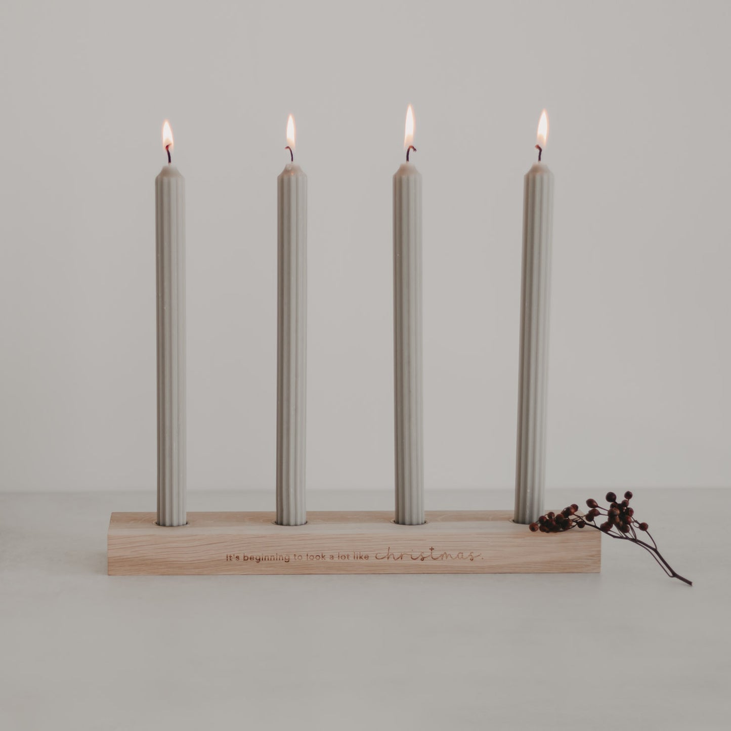 Adventskerzenbrett mit vier brennenden Kerzen und Gravur Christmas auf hellem Holz