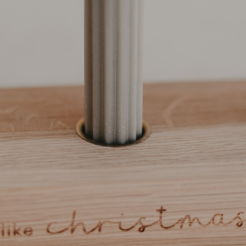 Nahaufnahme grauer Kerze im Holzkerzenhalter mit feiner Gravur Christmas