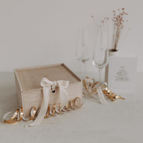 Holz-Erinnerungsbox Herz dekorativ verschlossen mit Stoffband, umgeben von festlicher Deko.