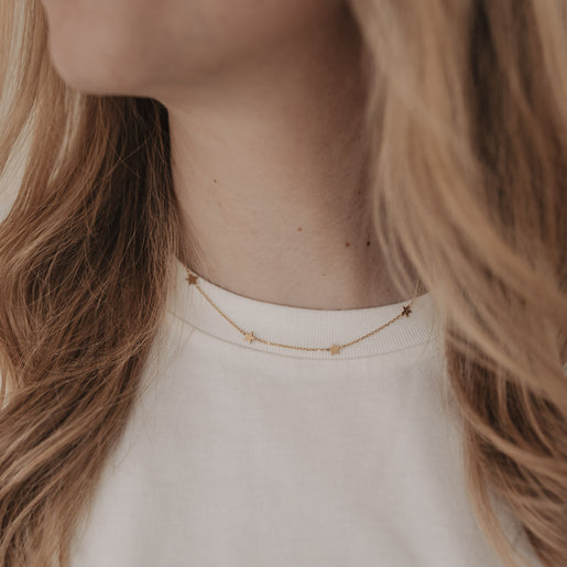 Filigrane goldene Sternkette Jackie getragen mit weißem Shirt – dezenter Schmuck für jeden Tag