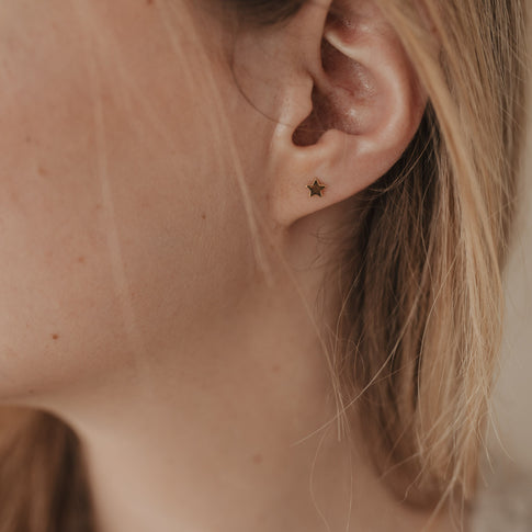 Nahaufnahme eines goldenen Stern-Ohrsteckers Jackie Gold am Ohr, filigraner Schmuck aus Goldvermeil.