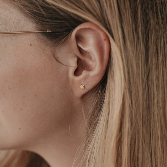 Zarter goldener Stern-Ohrstecker Jackie Gold am Ohr einer Frau, minimalistisches Schmuckdesign von Eulenschnitt.