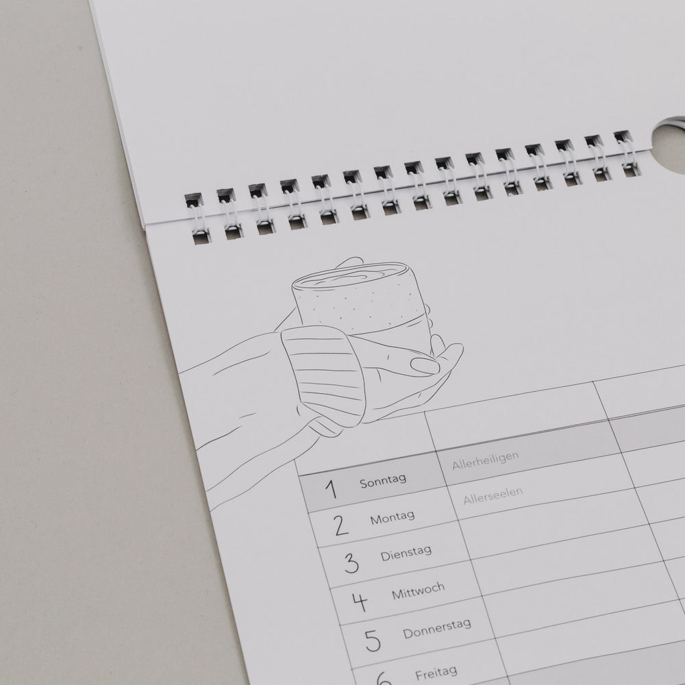 Familienkalender 2026 mit Illustration zweier Hände und Becher, Feiertage wie Allerheiligen in Spaltenübersicht sichtbar.