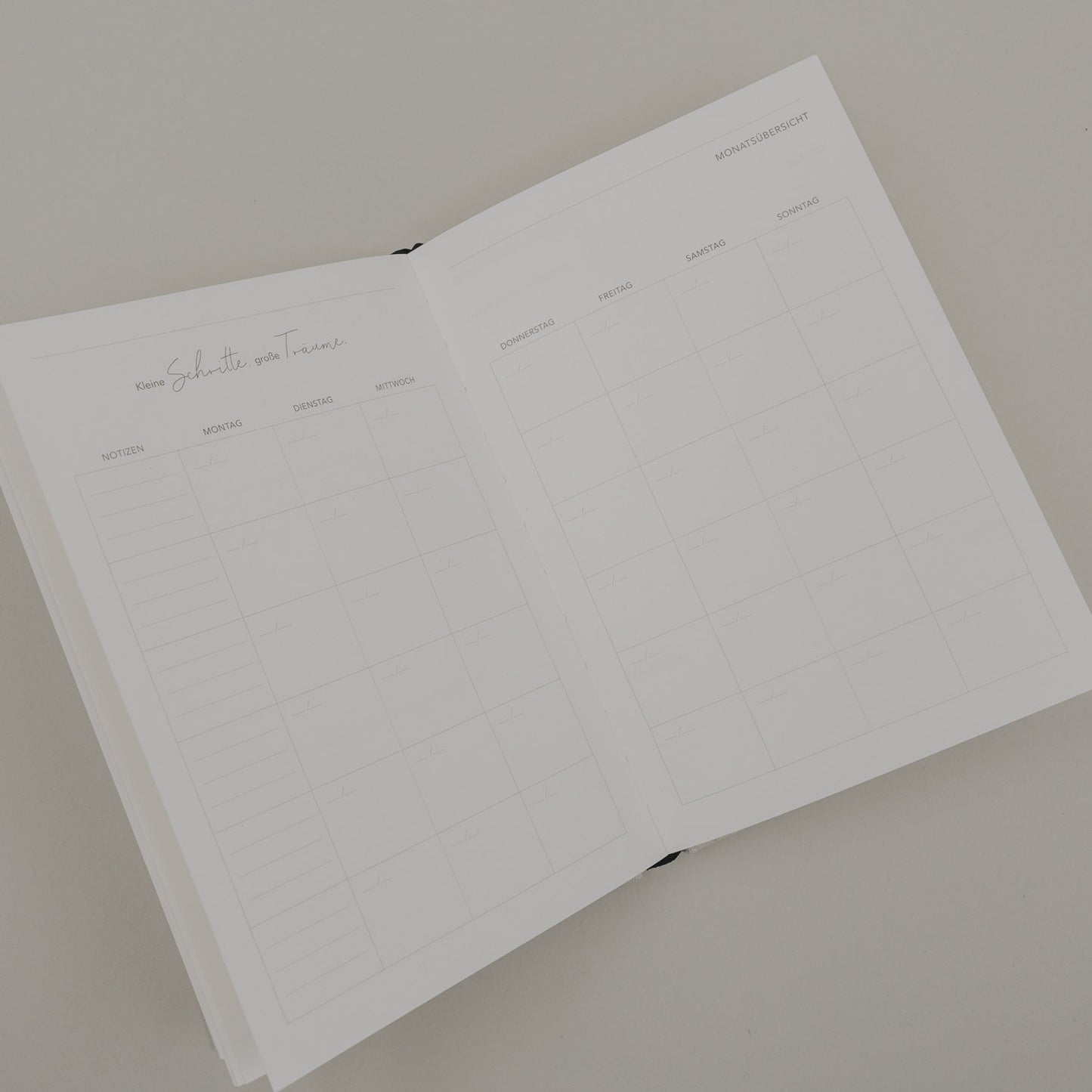 Geöffneter Kalender „Neues Glück“ mit Monatsübersicht und Wochenfeldern im schlichten, minimalistischen Design