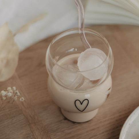 Eulenschnitt Bubble Glas mit schwarzem Herz-Print, gefüllt mit Iced Coffee und Eiswürfeln. 
