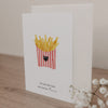 Klappkarte mit Illustration einer Pommes-Schachtel und dem Text 'Du bist das Salz auf meinen Pommes' auf hellem Holztisch