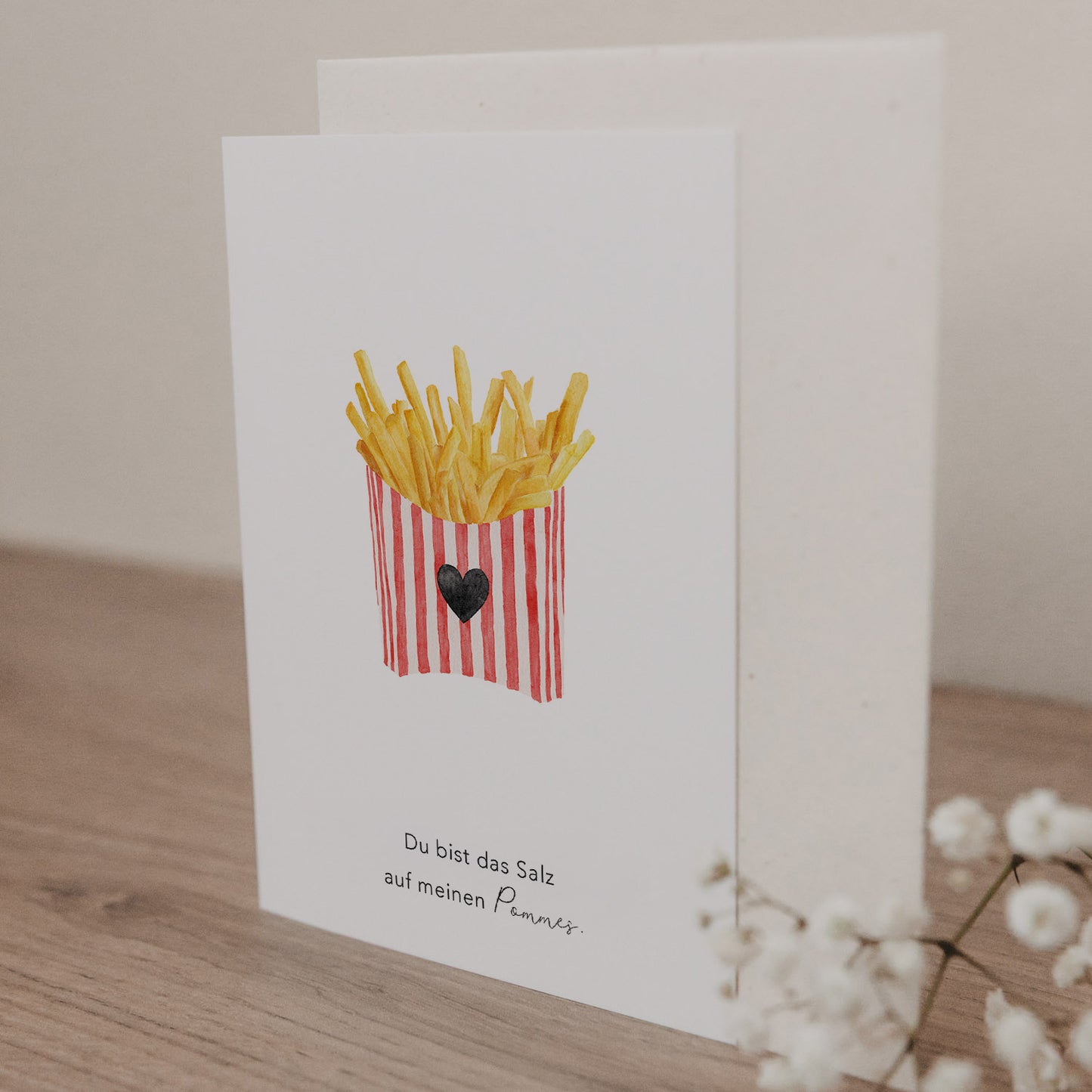 Klappkarte mit Illustration einer Pommes-Schachtel und dem Text 'Du bist das Salz auf meinen Pommes' auf hellem Holztisch