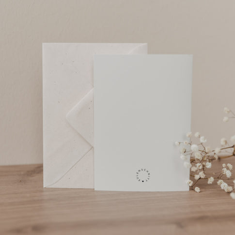 Weiße Klappkarte mit Umschlag auf Holztisch, minimalistisch gestaltet, Produktfoto der Hochzeitskarte 'Hochzeitsauto' von Eulenschnitt