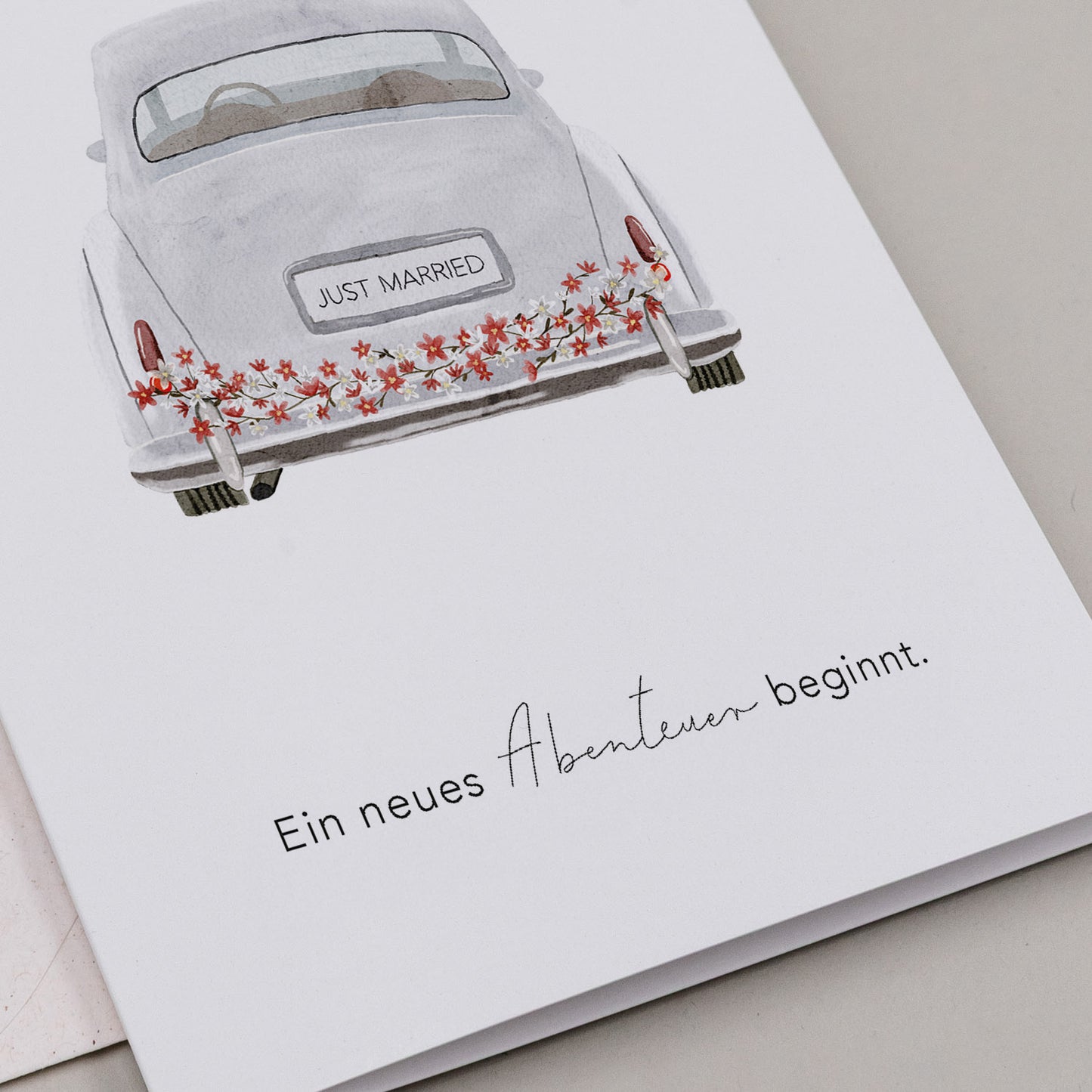 Klappkarte mit Aquarellzeichnung eines Hochzeitsautos mit 'JUST MARRIED'-Kennzeichen und Blumenschmuck, darunter der Text 'Ein neues Abenteuer beginnt.'