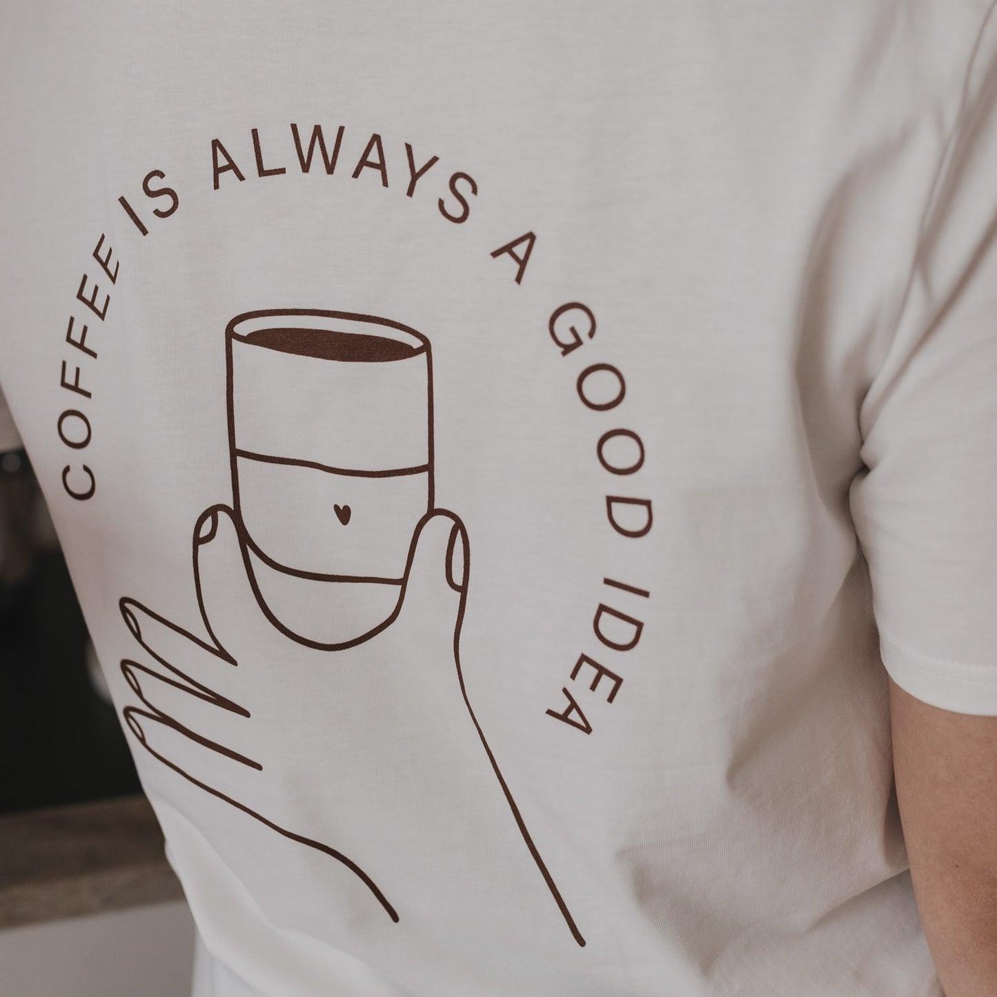 T-Shirt-Rückseite mit Kaffeetassen-Illustration und Spruch "Coffee is always a good idea" in Braun.