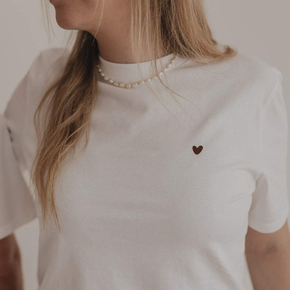 Detailansicht des Coffee T-Shirts mit kleinem braunen Herz auf der Brust bei Frau mit Perlenkette