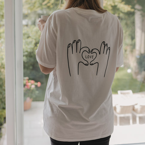 Rückenansicht des LOVE-T-Shirts vor einem Fenster mit Gartenblick