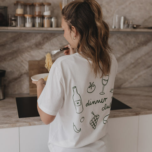 Frau mit Dinner Club Shirt von hinten, isst Spaghetti – Rückendruck mit Dinner-Motiven.