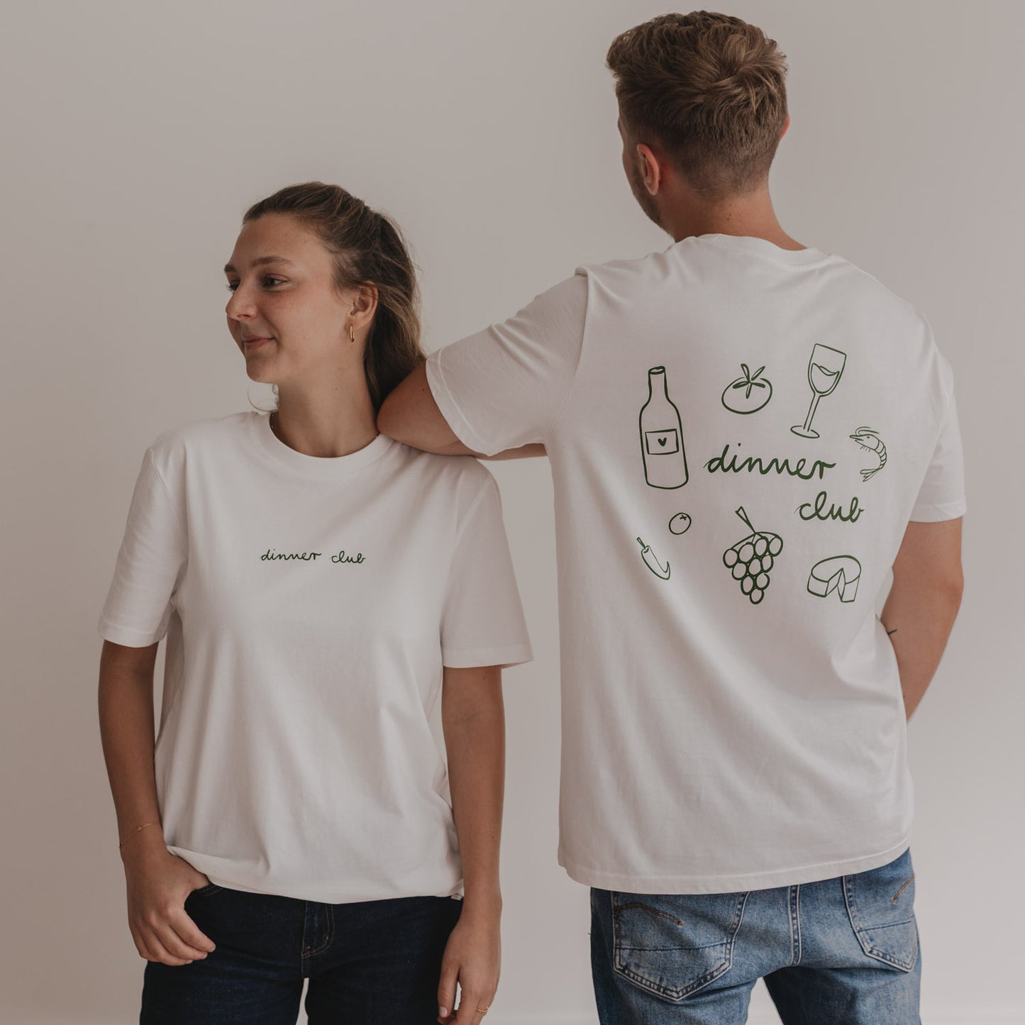 Zwei Personen tragen  Dinner Club Shirt in Weiß mit grünem Front- und Rückenprint – lässig und modern