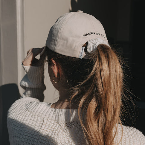 Rückansicht beige Cap mit Stick „Hab einen tollen Tag“ und Pferdeschwanz