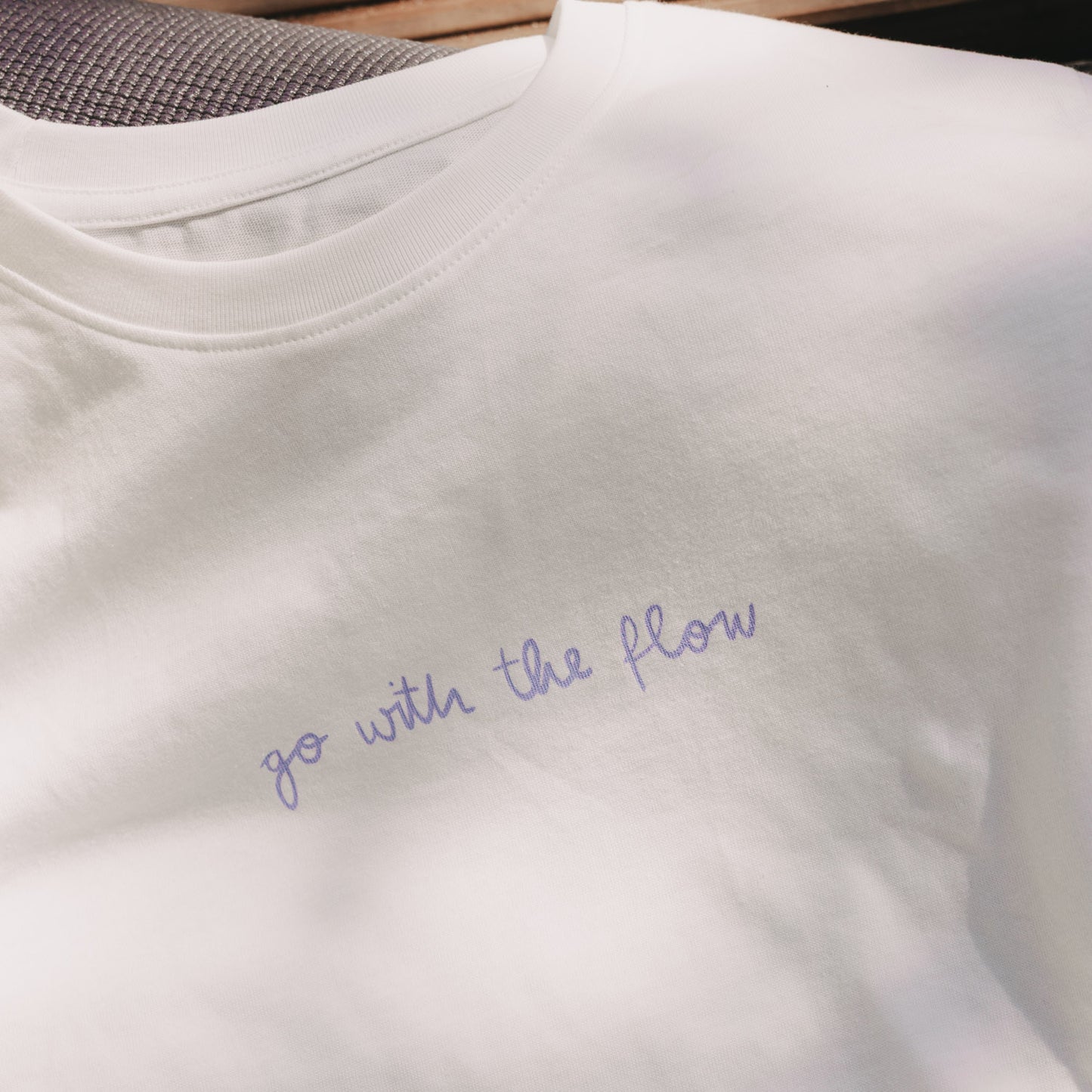 Detailansicht: weißes T-Shirt mit Schriftzug „go with the flow“ vorne