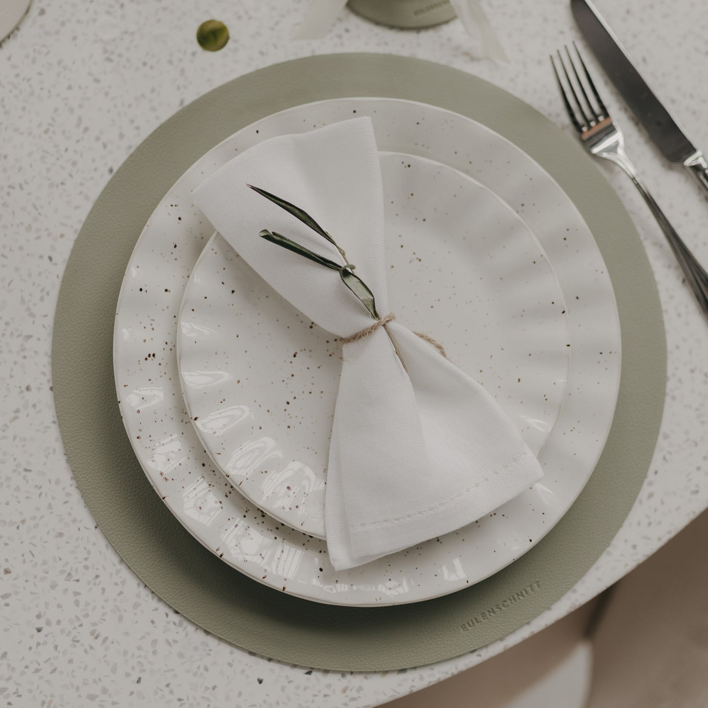 Helles grünes Platzset mit Herzprägung unter modernem Teller-Set