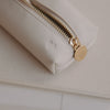 Detail der cremefarbenen Federtasche mit Herzprägung und goldenem Reißverschluss