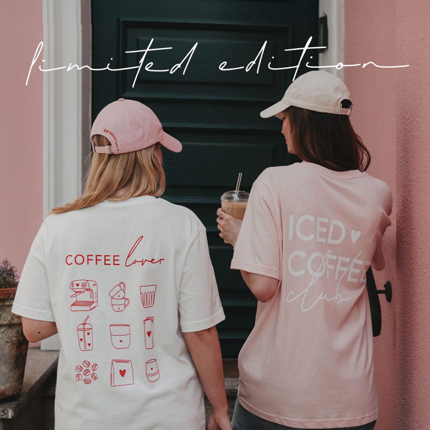 Zwei Frauen von hinten in weißem „Coffee Lover“-Shirt und rosafarbenem „Iced Coffee Club“-Shirt vor einer rosa Hauswand.