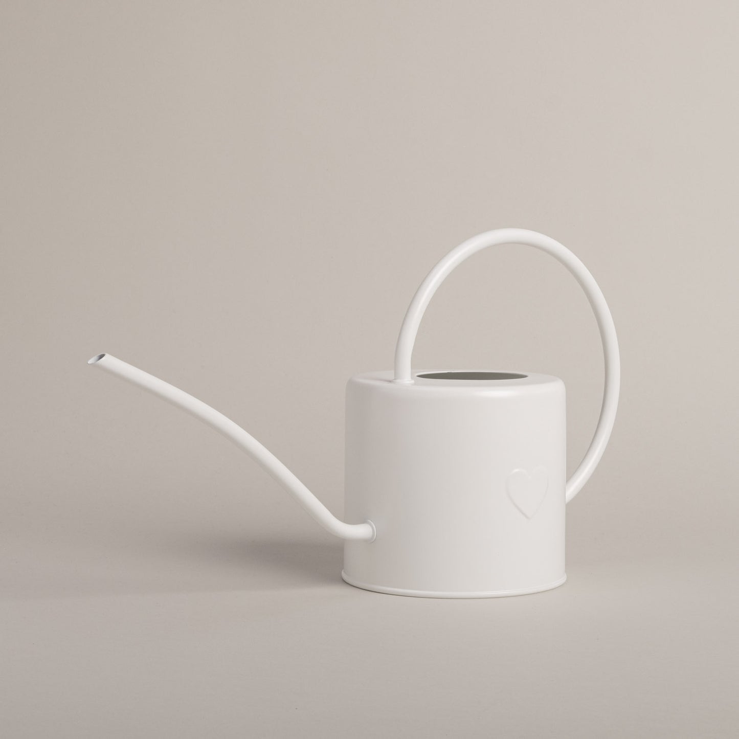 Metallgießkanne in Weiß mit filigranem Henkel und geprägtem Herz auf hellem Untergrund