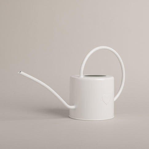 Metallgießkanne in Weiß mit filigranem Henkel und geprägtem Herz auf hellem Untergrund