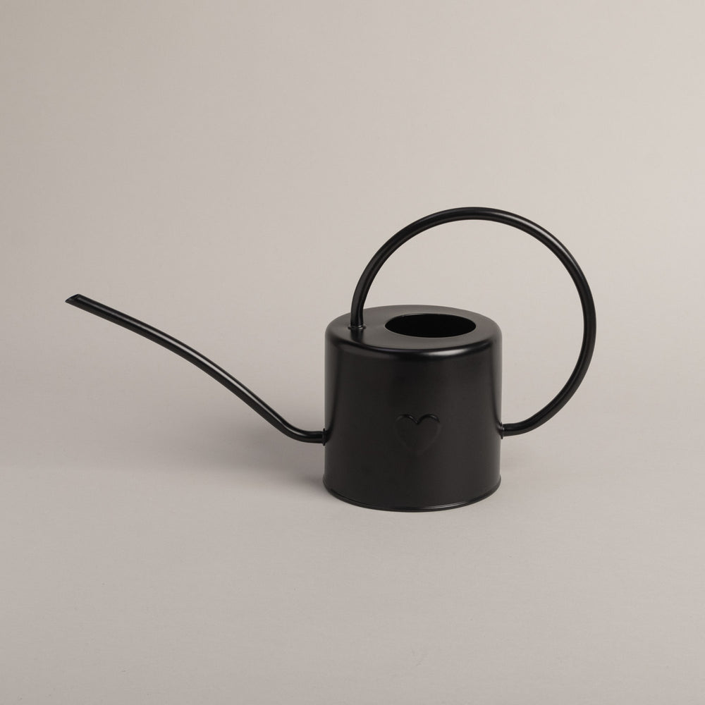 Schwarze Gießkanne mit Herz-Prägung, seitlich fotografiert