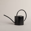 Schwarze Metallgießkanne mit rundem Henkel, seitliche Ansicht