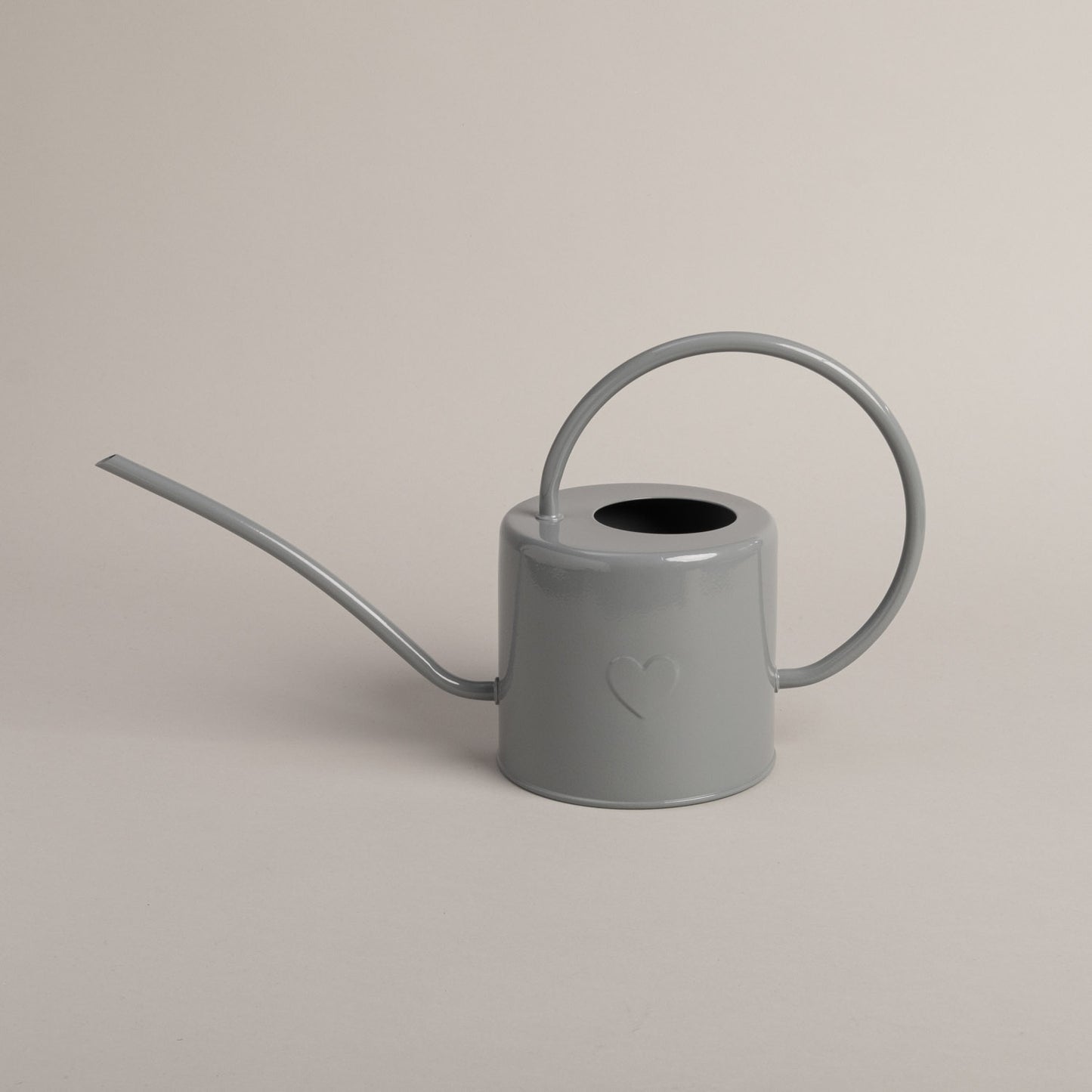 Graue Metallgießkanne mit langem Ausguss und rundem Griff – schlichtes Design mit geprägtem Herzmotiv.