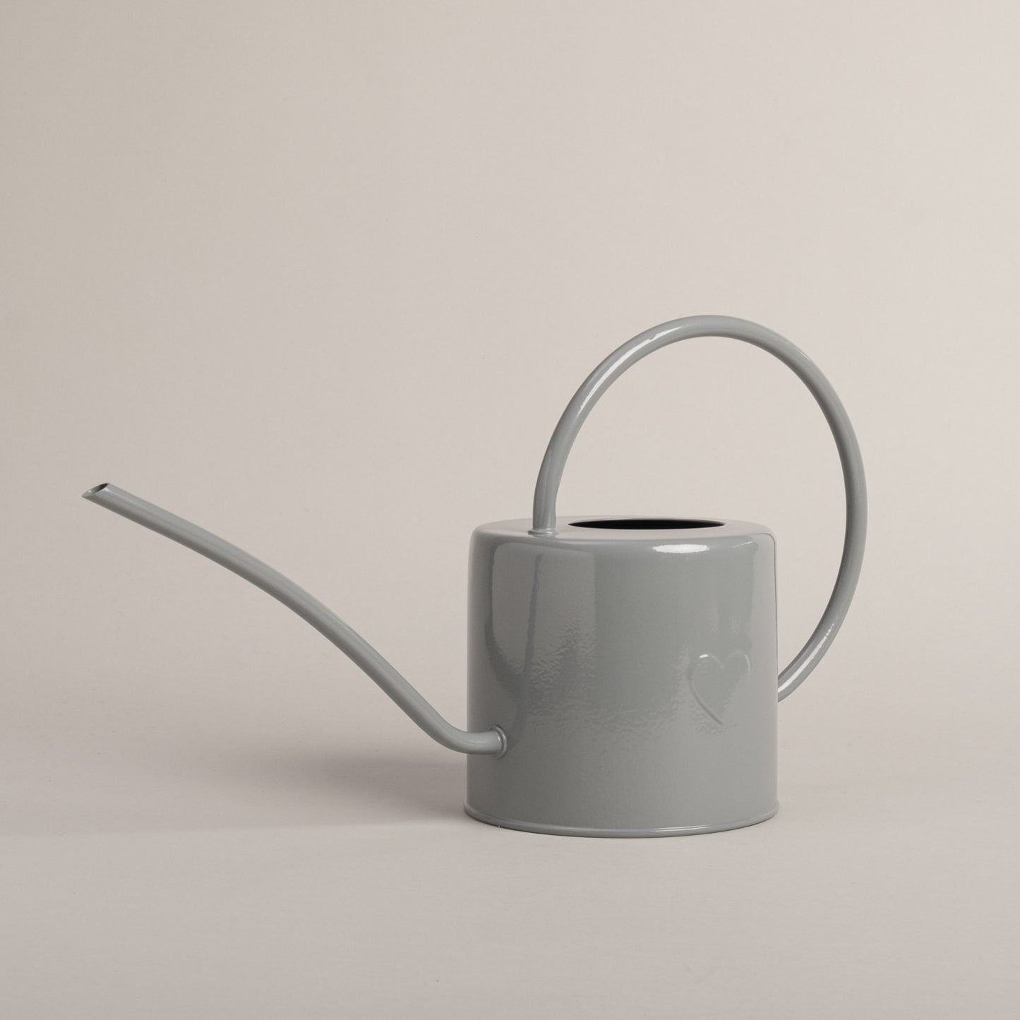 Graue Gießkanne aus Metall mit Herzdetail, seitlich fotografiert – stilvolles Accessoire für Haus und Garten.