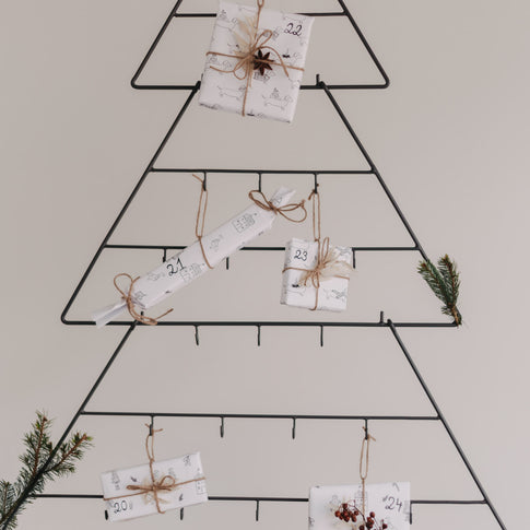 Mehrere Geschenke und Zweige am Adventskalender Tanne dekoriert.