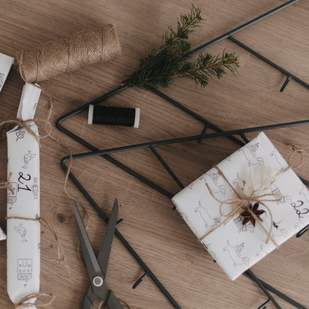 Detailfoto von Adventskalender Tanne mit Geschenk und Deko auf Holztisch.