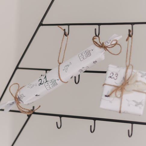 Verpacktes Geschenk mit Nummer 21 am Adventskalender Tanne befestigt.