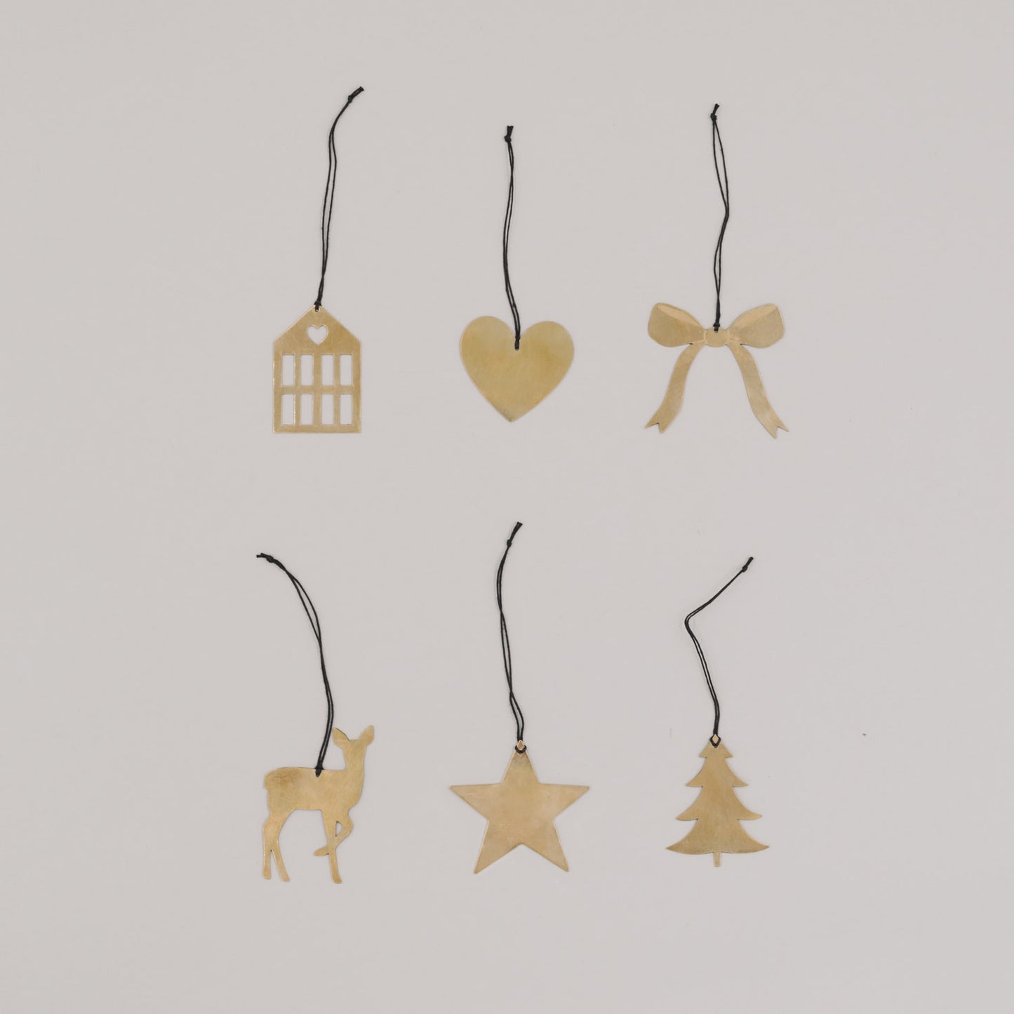 Sechs goldene Metallanhänger mit schwarzem Band in verschiedenen Formen auf hellem Hintergrund.