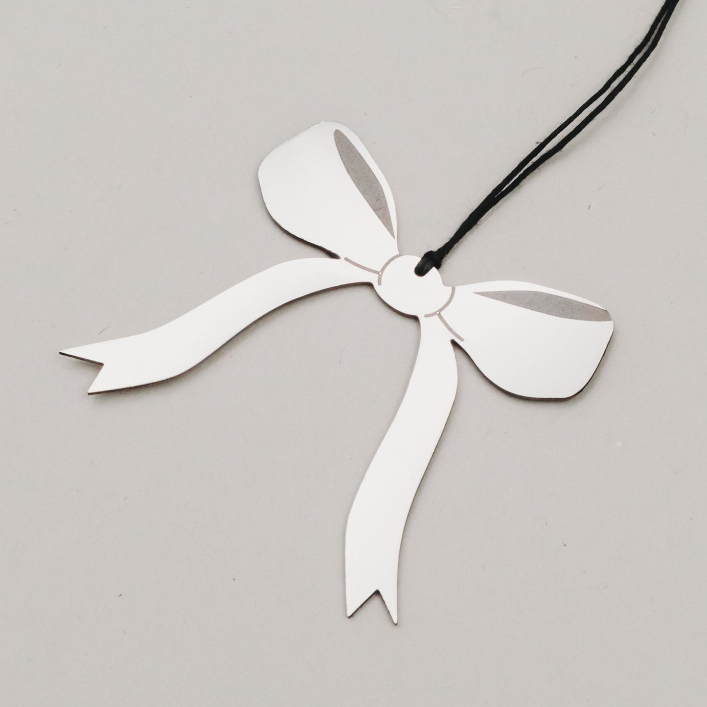 Nahaufnahme des Schleifenanhängers in Silber mit schwarzem Band, auf hellem Hintergrund fotografiert.