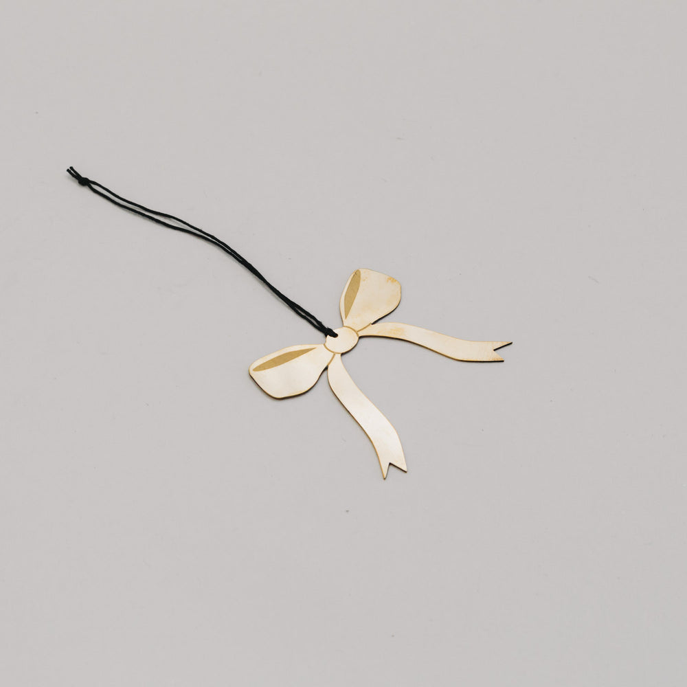 Goldene Schleife aus Metall in schräger Perspektive, filigran gearbeitet mit schwarzer Aufhängung.