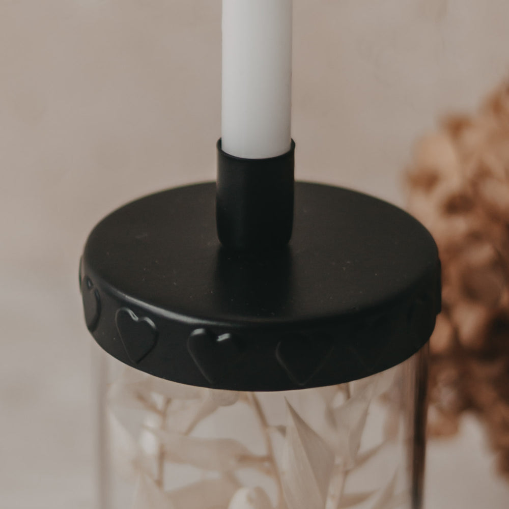 Nahaufnahme Kerzenhalter mit Kerze:
Kerzenöffnung des schwarzen Deckels mit eingelegter Tannenbaumkerze.