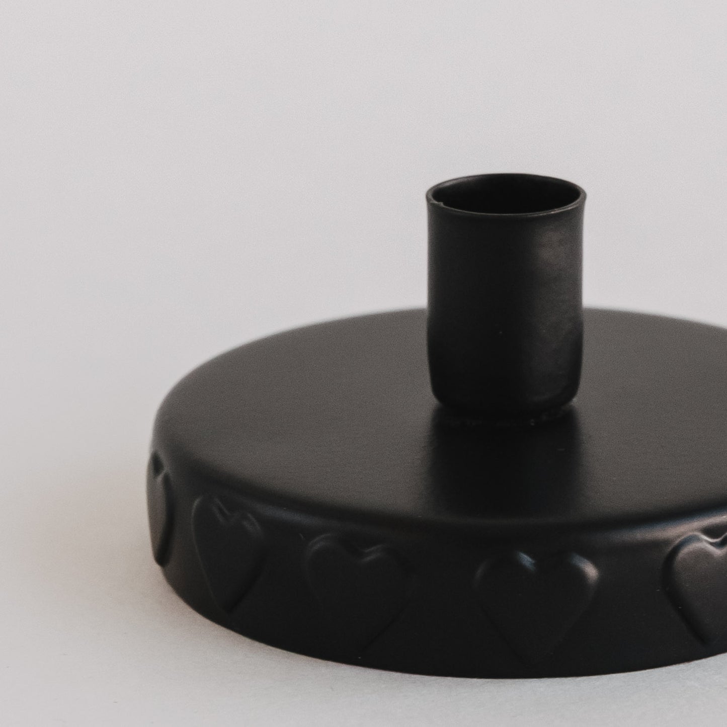 Detailaufnahme Kerzenöffnung:
Detailansicht des schwarzen Kerzenhalters mit geprägten Herzen.