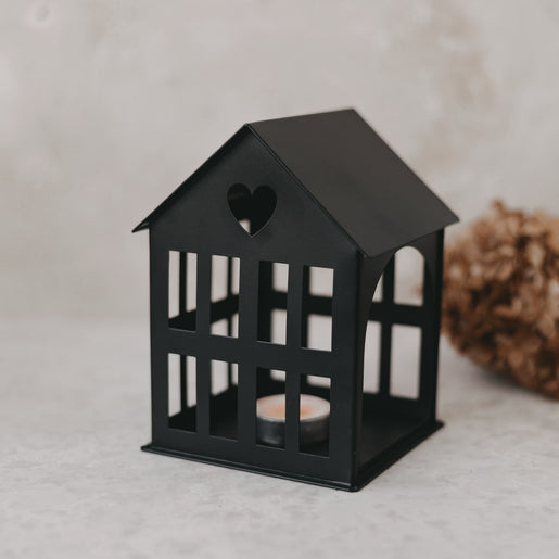 Nahaufnahme des schwarzen Metallhauses mit Herz-Ausschnitt im Dach und Teelicht – edle Tischdekoration.