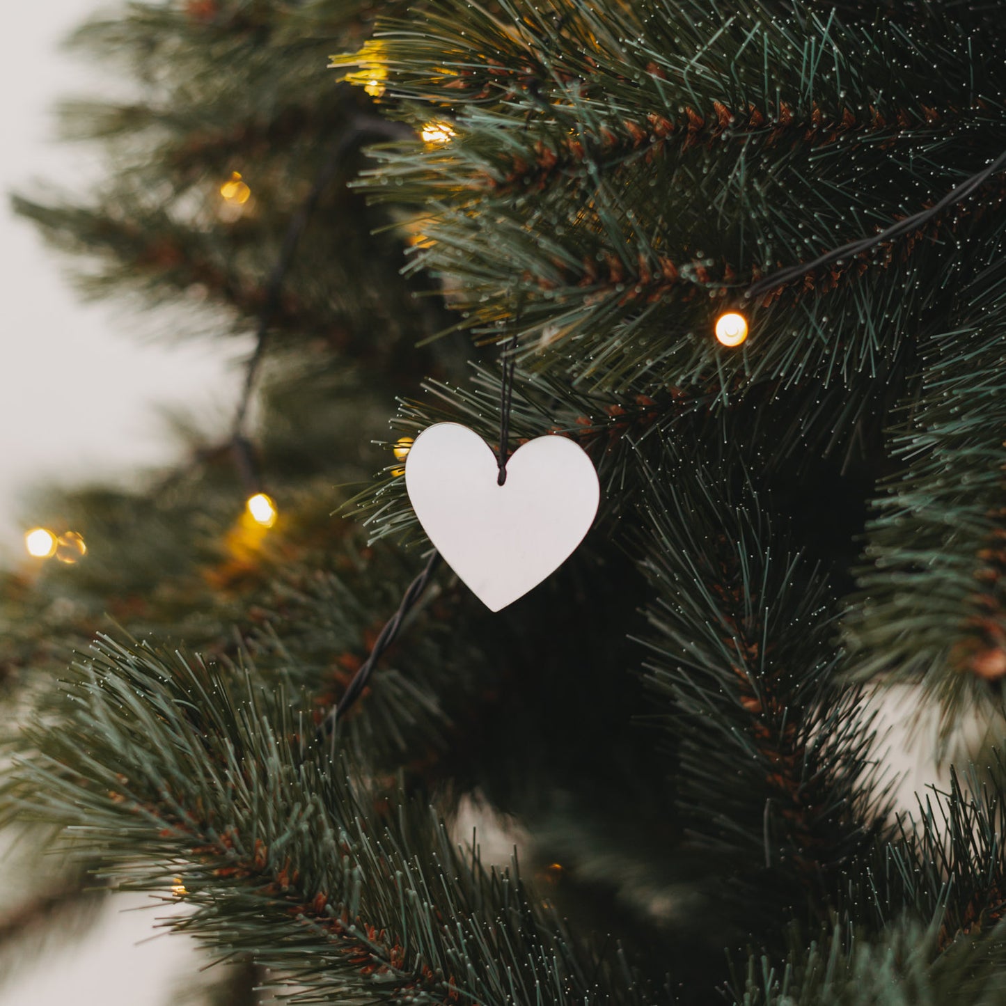 Silberner Herzanhänger am Weihnachtsbaum mit Lichterkette – festliche Dekoration 