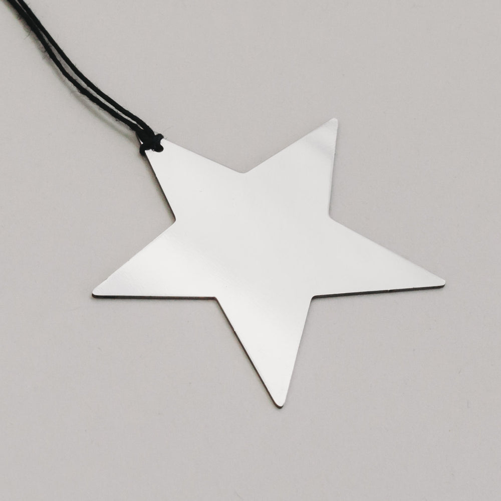 Detailaufnahme des silbernen Metallsterns mit schwarzer Schnur, zeigt reflektierende Oberfläche.